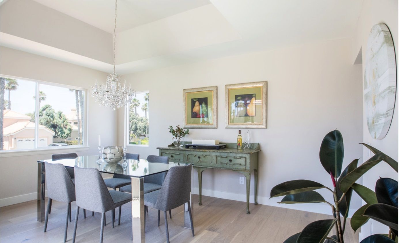 A dining room with a table and chairs and a plant.