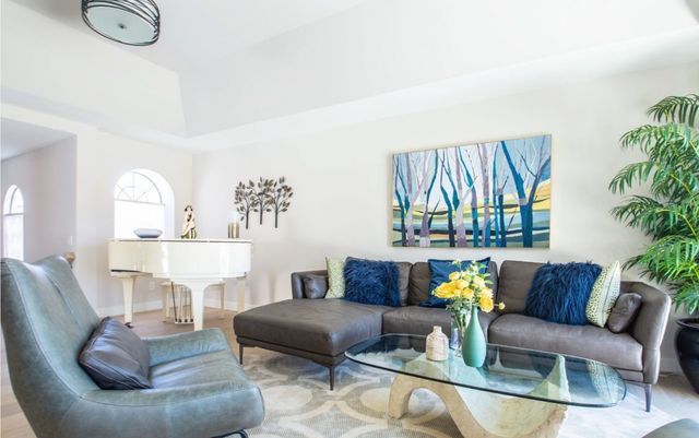A living room with a couch , chair , coffee table and piano.