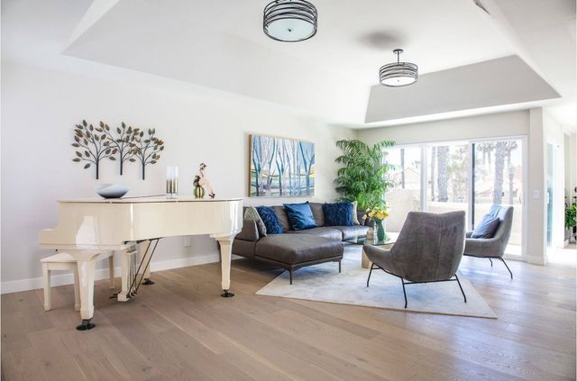 A living room with a piano , couch , chairs and sliding glass doors.
