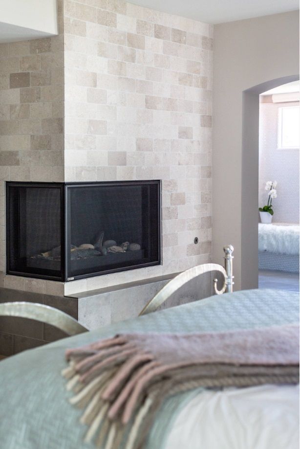 A bedroom with a fireplace and a bed with a blanket on it