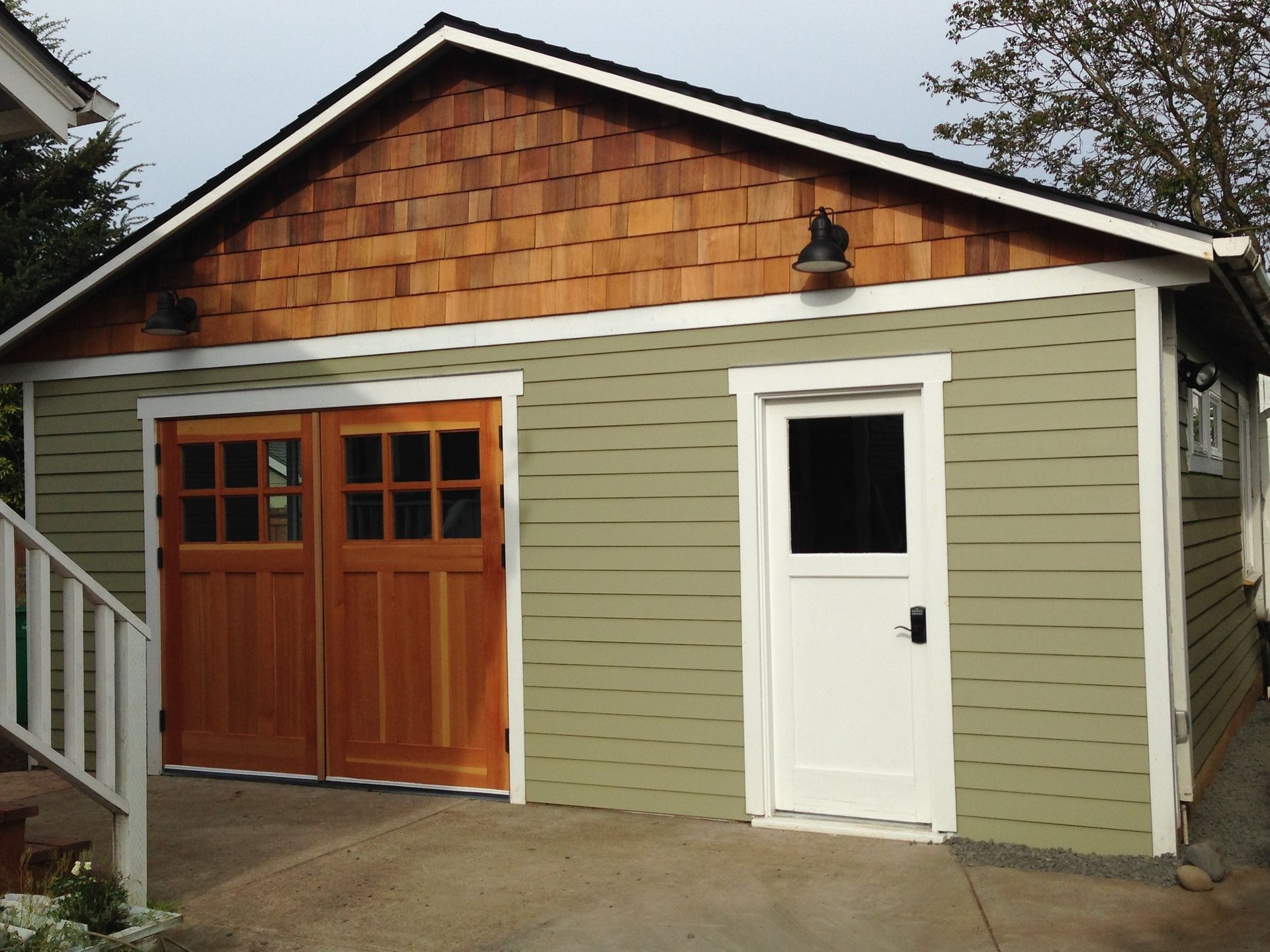 A green garage with a wooden door and a white door