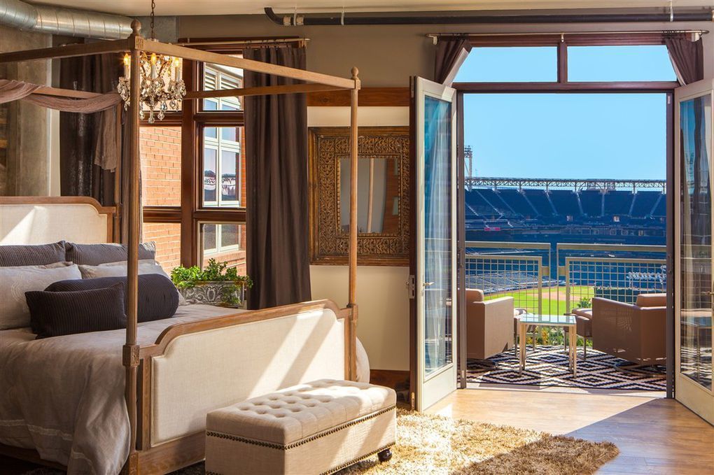 A bedroom with a four poster bed and a view of a baseball stadium.
