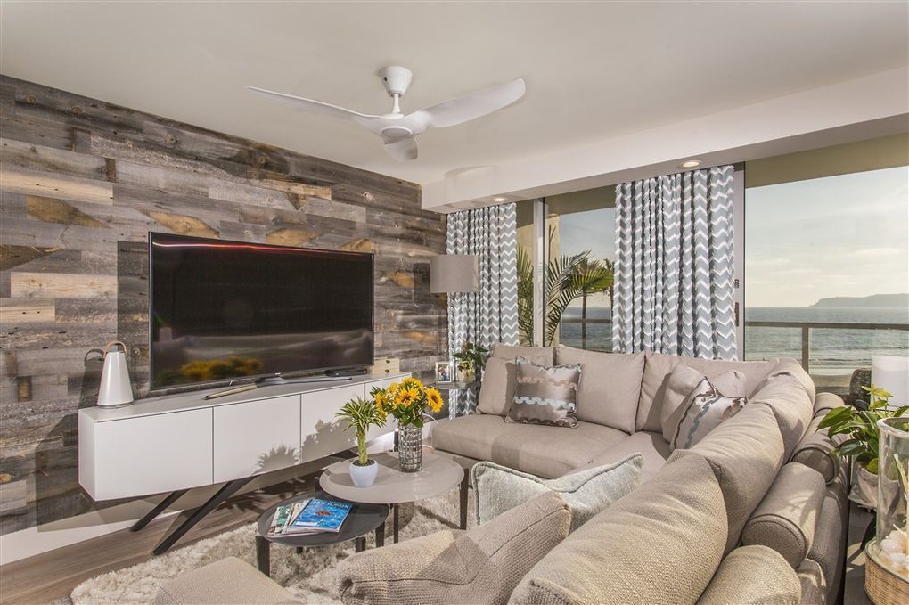 A living room with a couch , television , and ceiling fan.