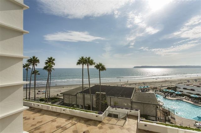 A view of the ocean from a balcony with palm trees