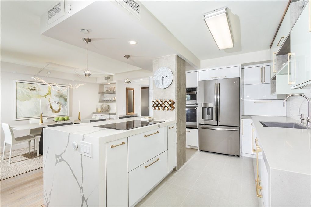 A kitchen with white cabinets, stainless steel appliances, and a large island.