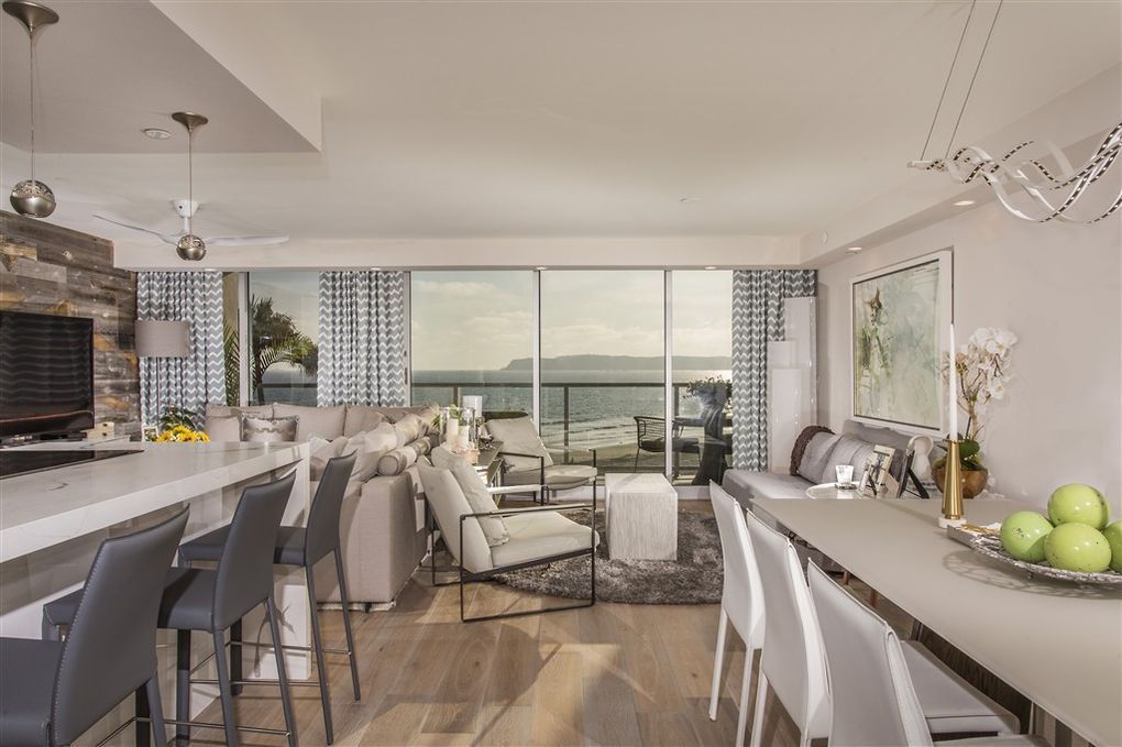 A living room with a dining table and chairs and a large window.