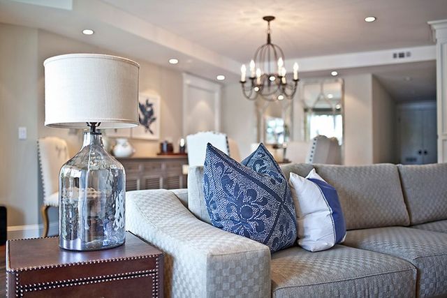 A living room with a couch , two lamps , and a chandelier.