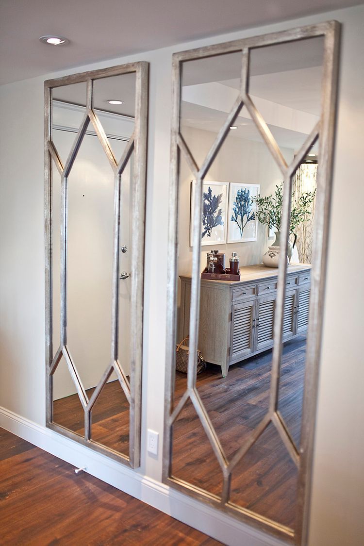 Two large mirrors are hanging on a wall in a hallway.
