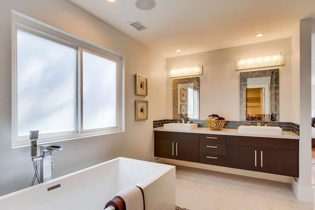 A bathroom with two sinks , a tub , and two mirrors.