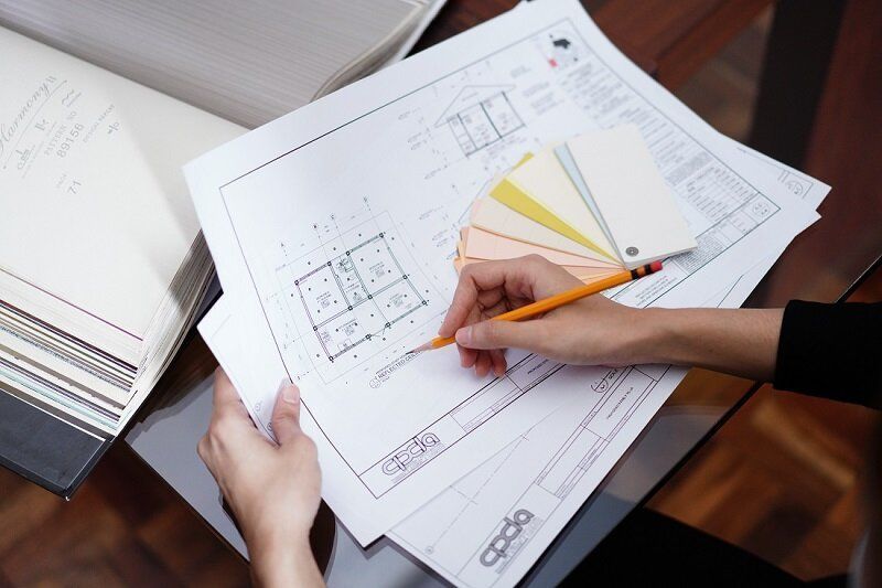 A woman makes notes on a set of blueprints.