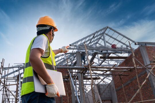 A construction worker is standing in front of a building under construction.
