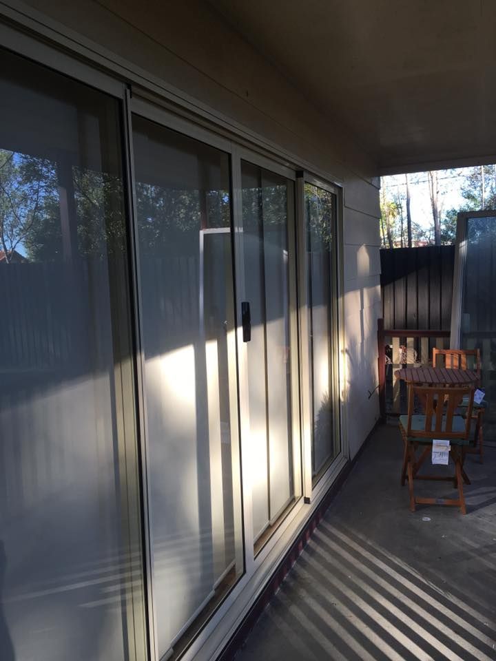 A Patio With Sliding Glass Doors And A Table And Chairs — Screen Factory In Murwillumbah, NSW
