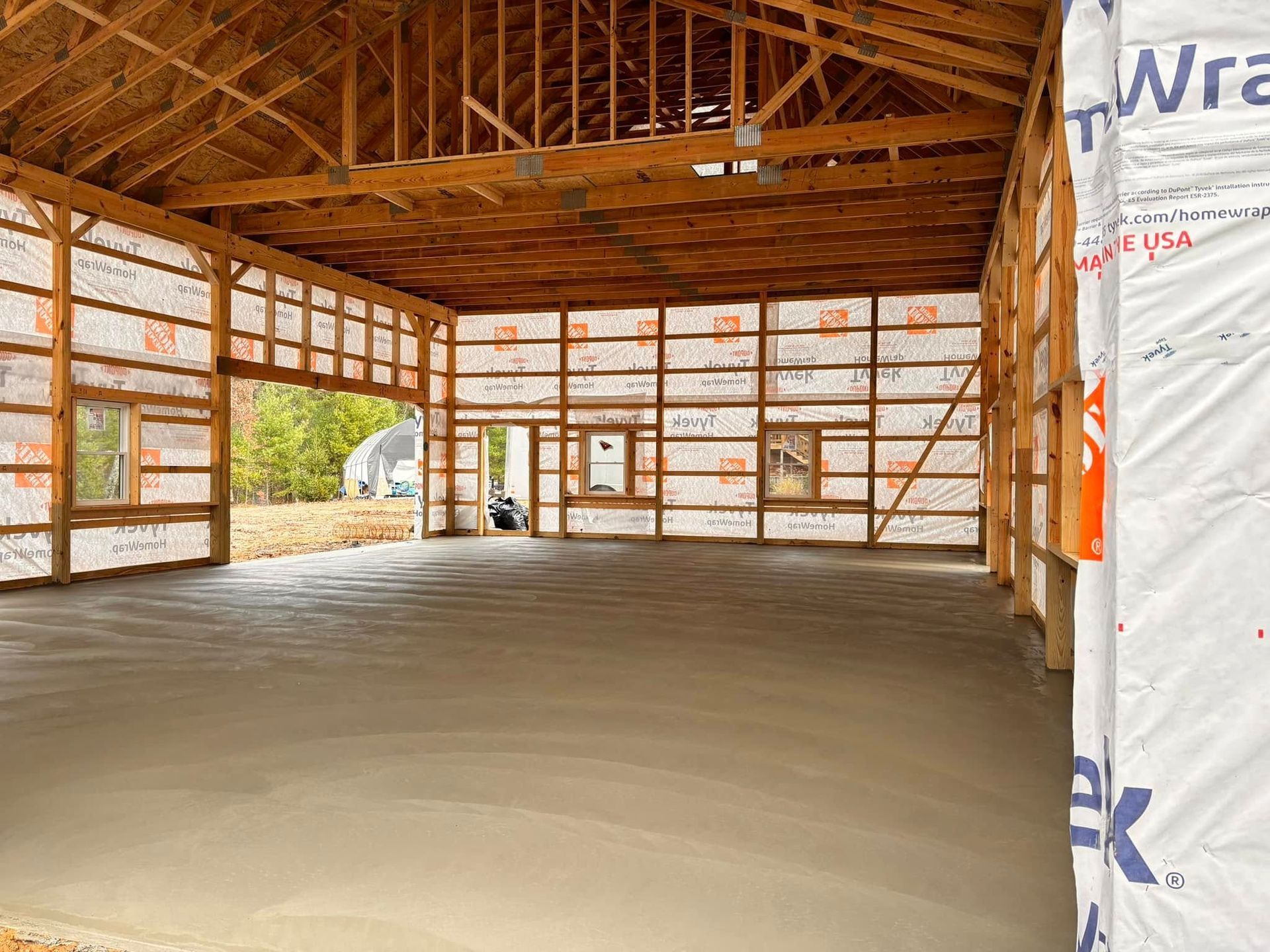 Interior of a new, unfinished garage. Concrete floor, wooden framing, and insulation are visible.