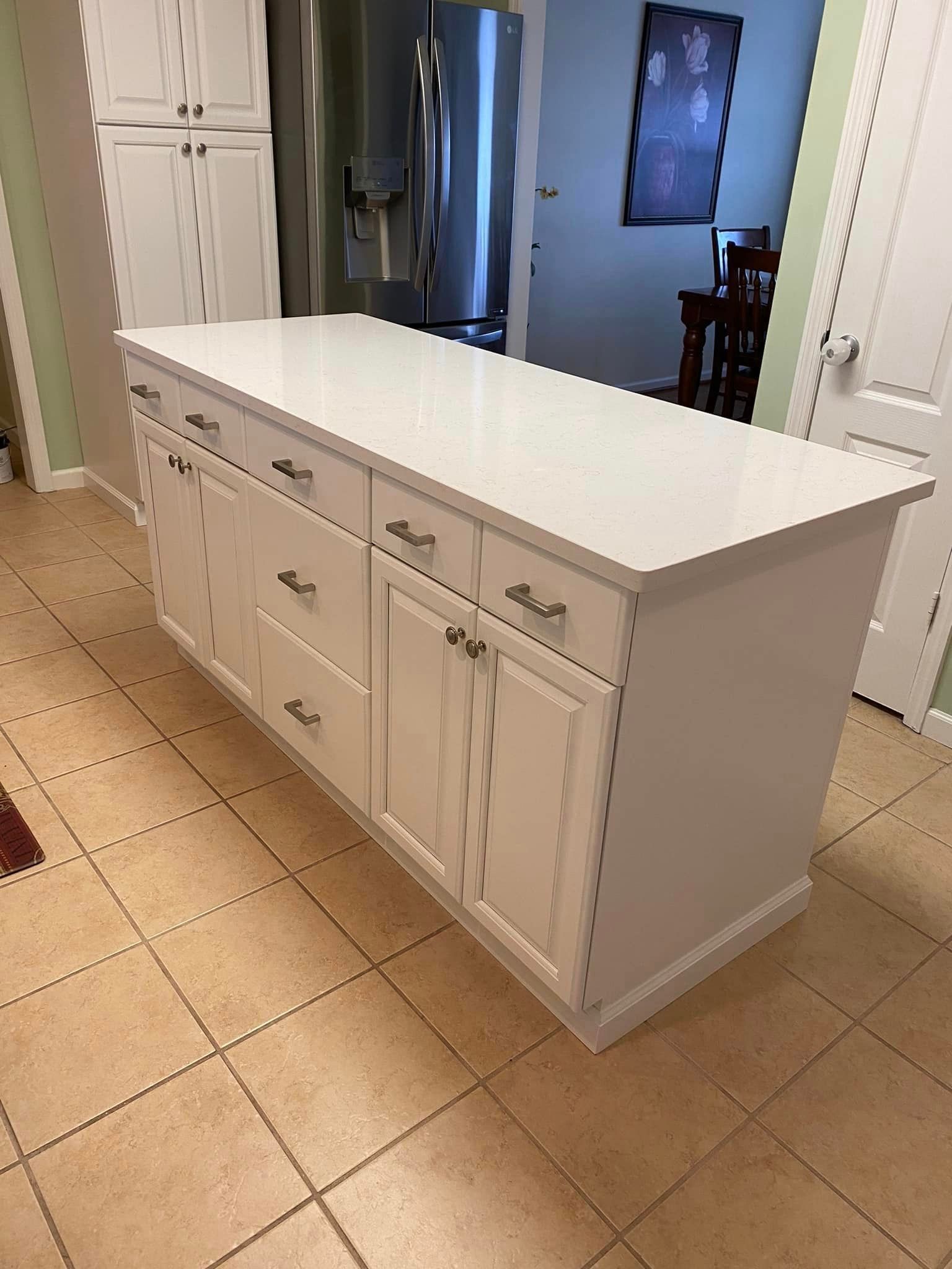 White kitchen island with drawers and cabinets; set on tile floor.