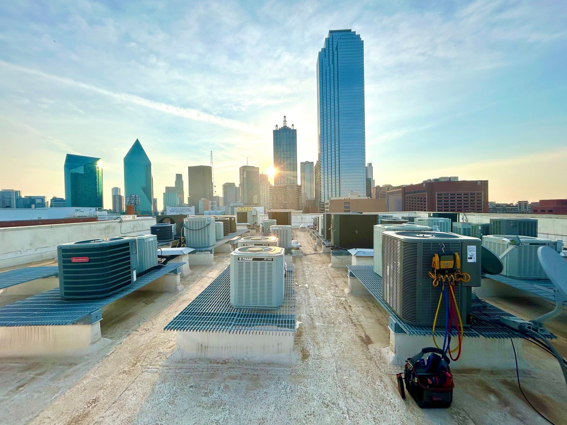 A rooftop with a lot of air conditioners and a city skyline in the background.