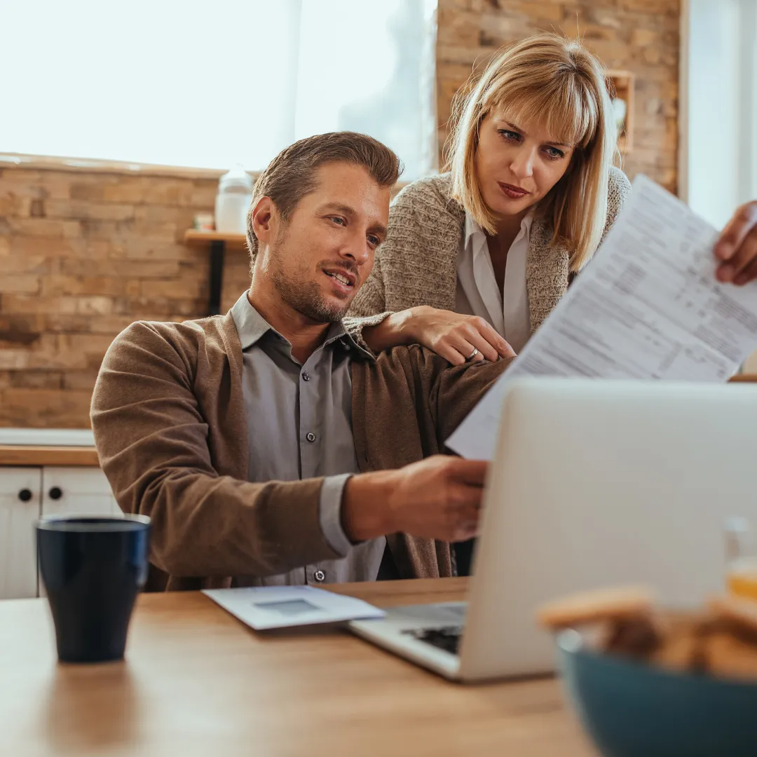 A man and a woman are looking at a laptop computer.