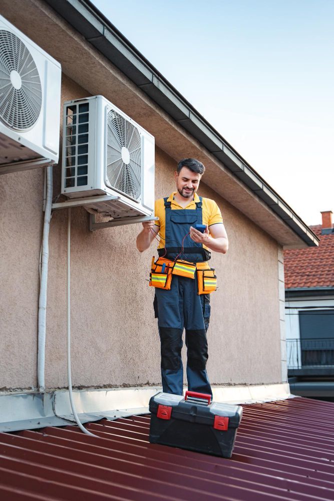 HVAC technician on roof, inspecting AC unit with phone. Tool belt, toolbox, sunny sky, beige wall.