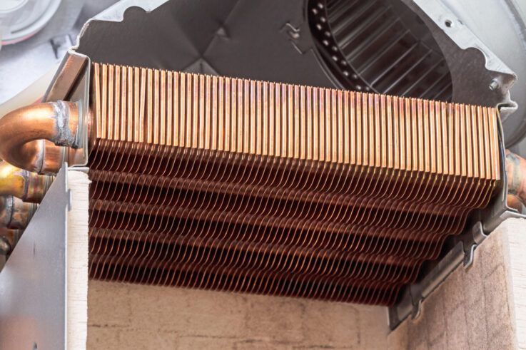 Copper heat exchanger with fins inside a furnace.