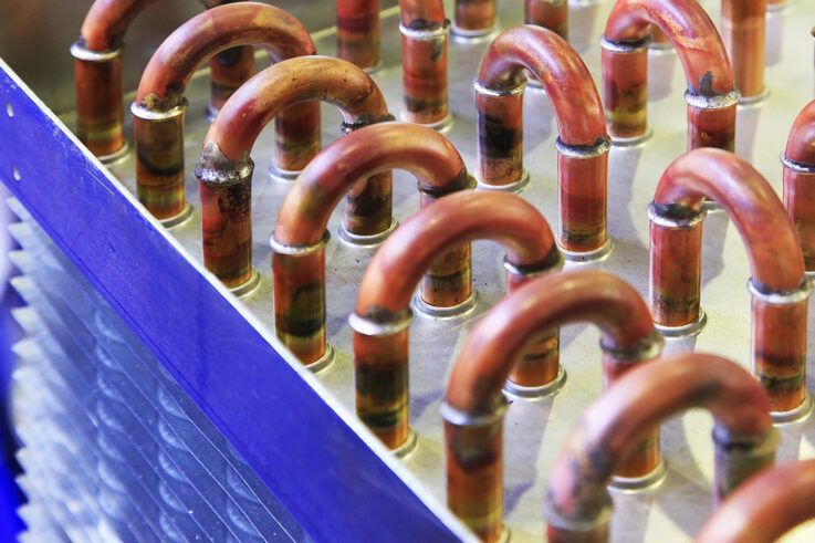 Copper tubes in a blue metal frame, part of a cooling system.