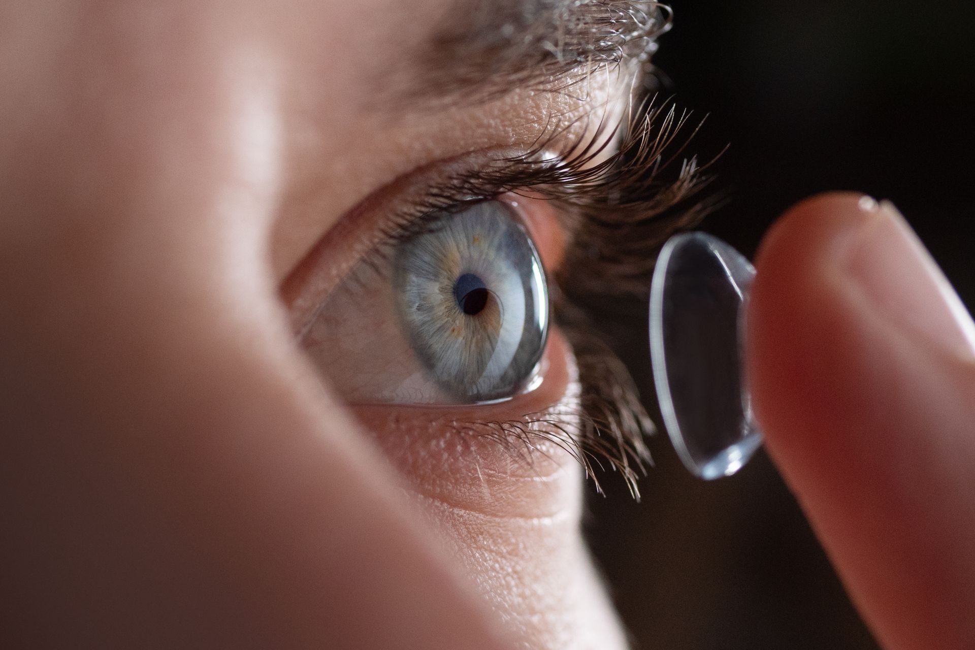 Close-up of a man putting on prescribed contact lenses in his blue eye. Close-up of a man putting on prescribed contact lenses in his blue eye.