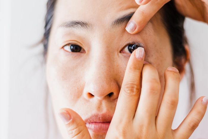 A woman is putting on her contact lens.
