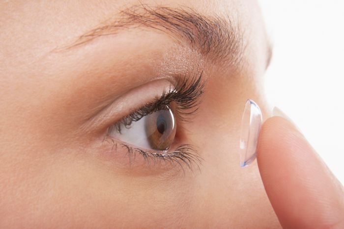 A woman is putting on a contact lens.