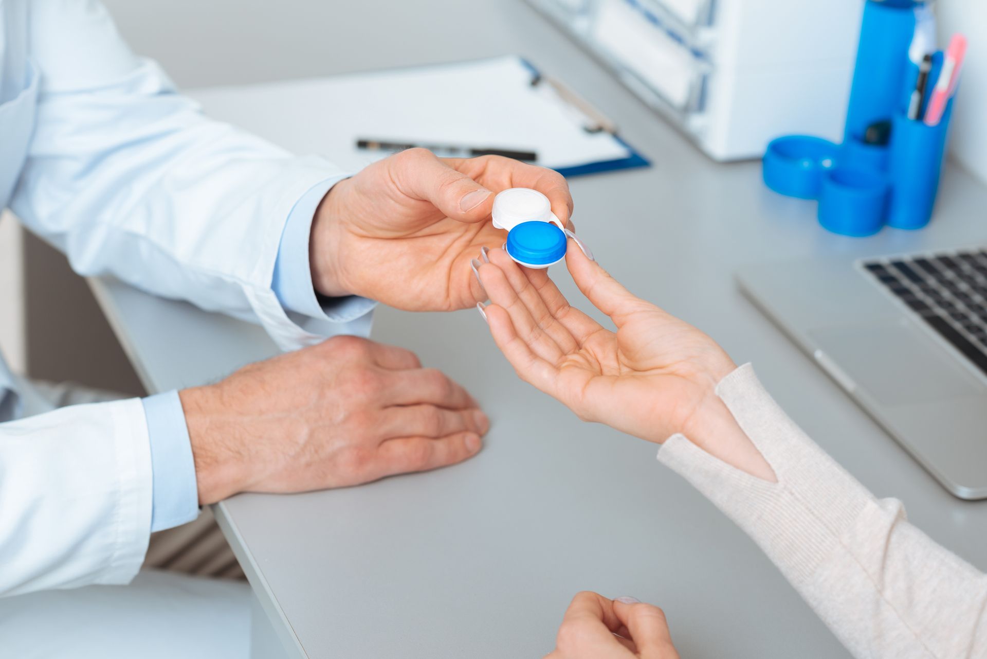 Ophthalmologist giving contact lens to patient in clinic.