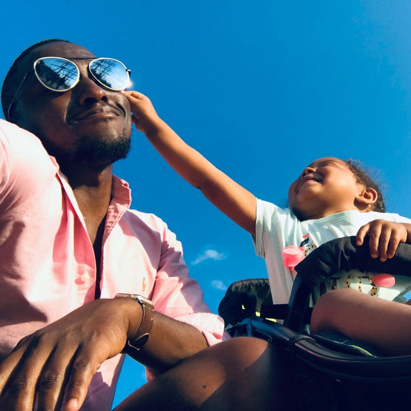 A man wearing sunglasses holds a little girl in a stroller