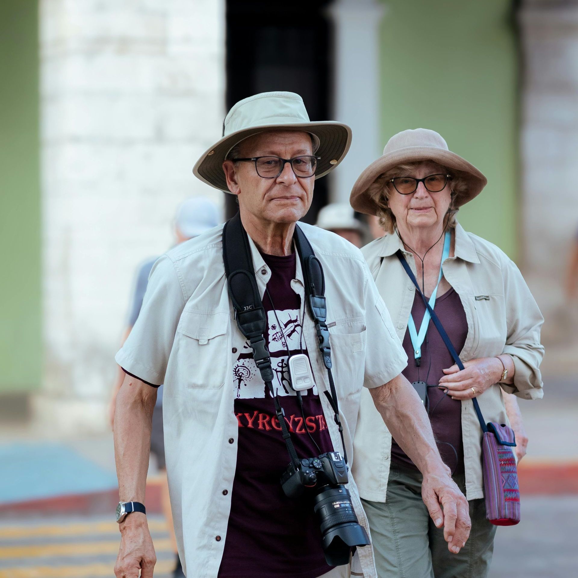 A man wearing a hat and glasses is walking with a woman wearing a hat.