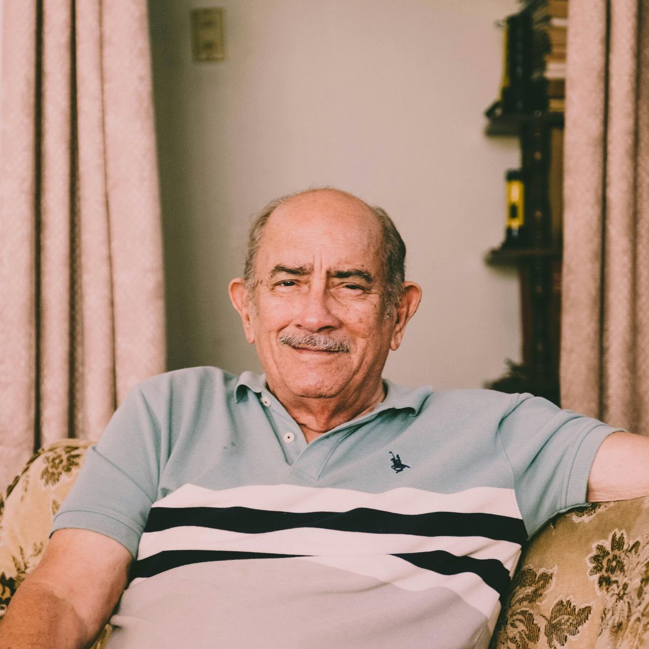 A bald man with a mustache is sitting on a couch