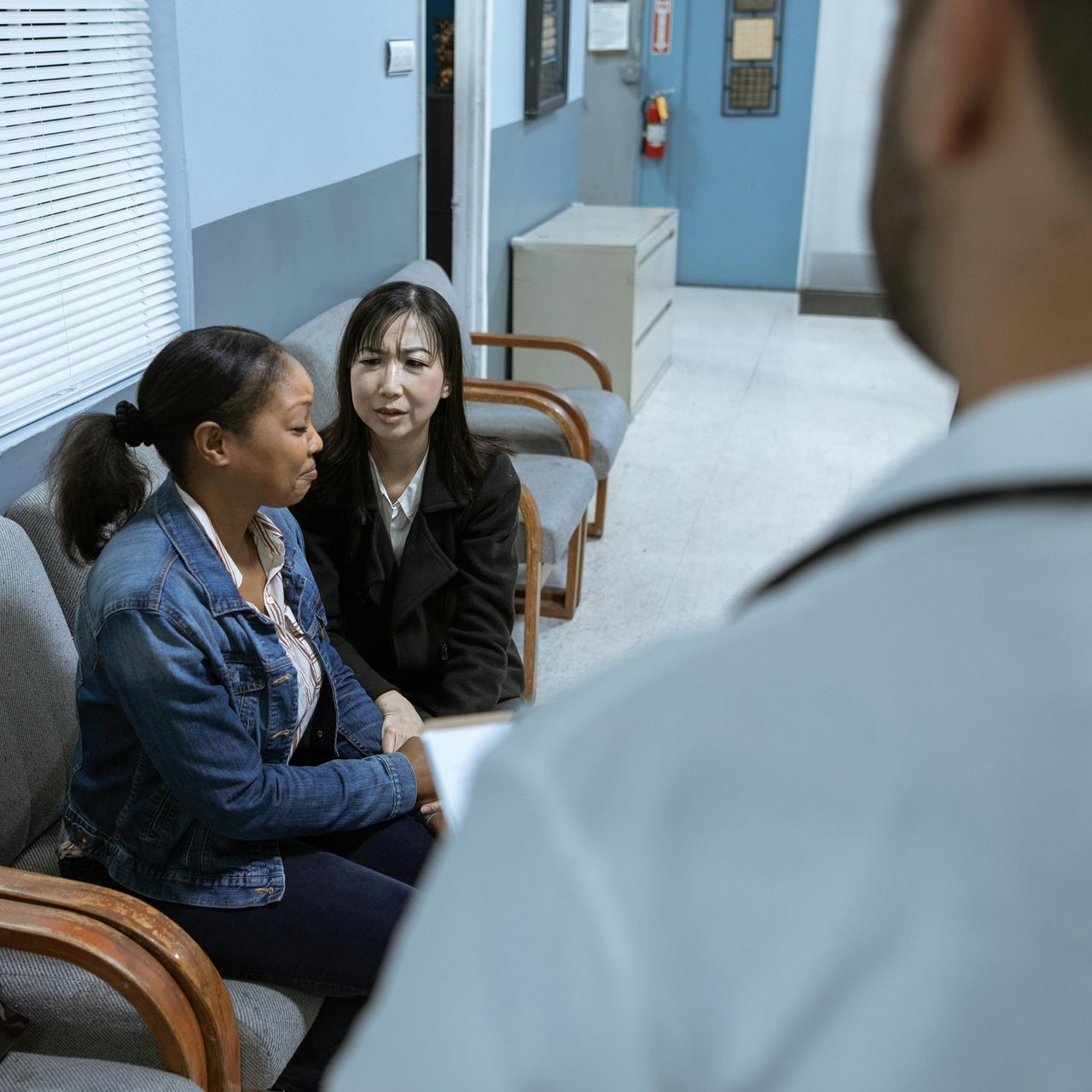 A doctor is talking to two women in a waiting room