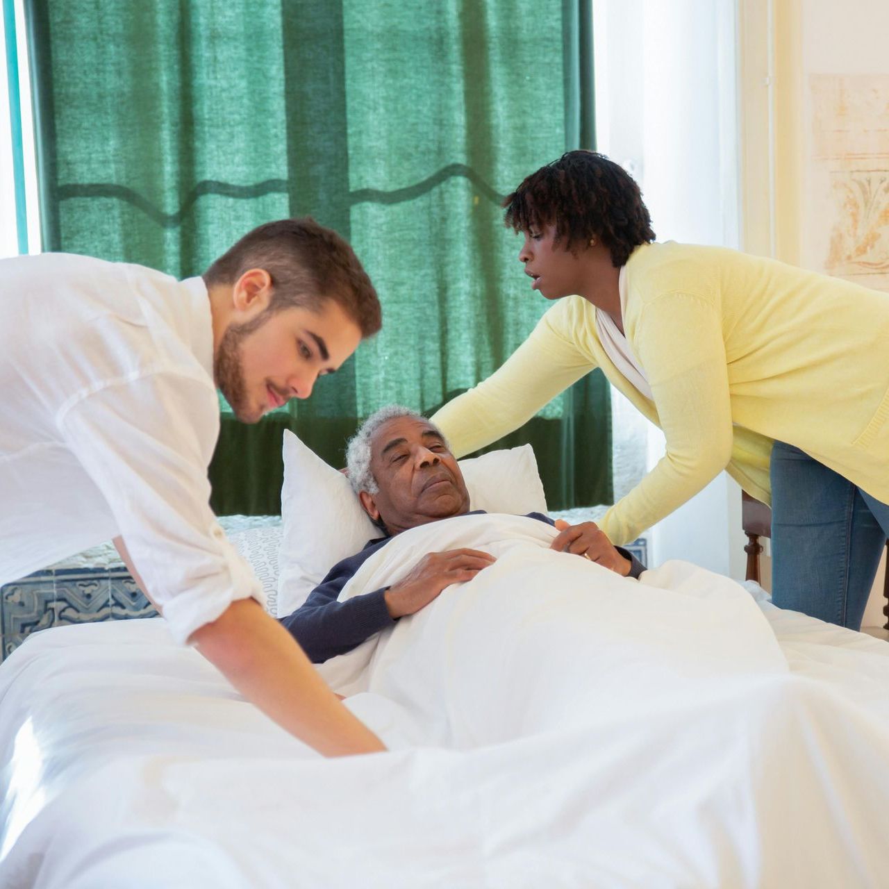 A man and a woman are putting a man in a hospital bed