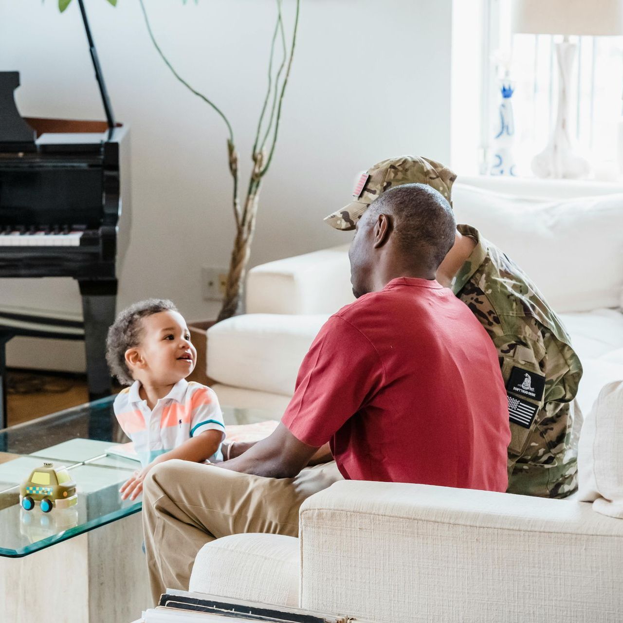 A man in a military uniform sits on a couch with a child