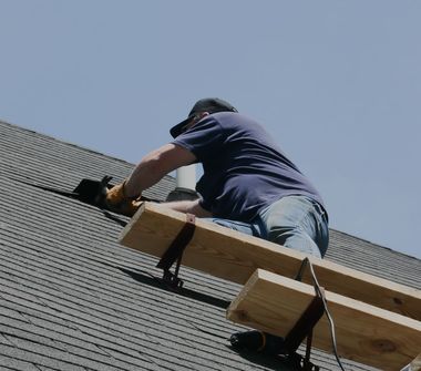 A man is working on a roof with a ladder attached to it