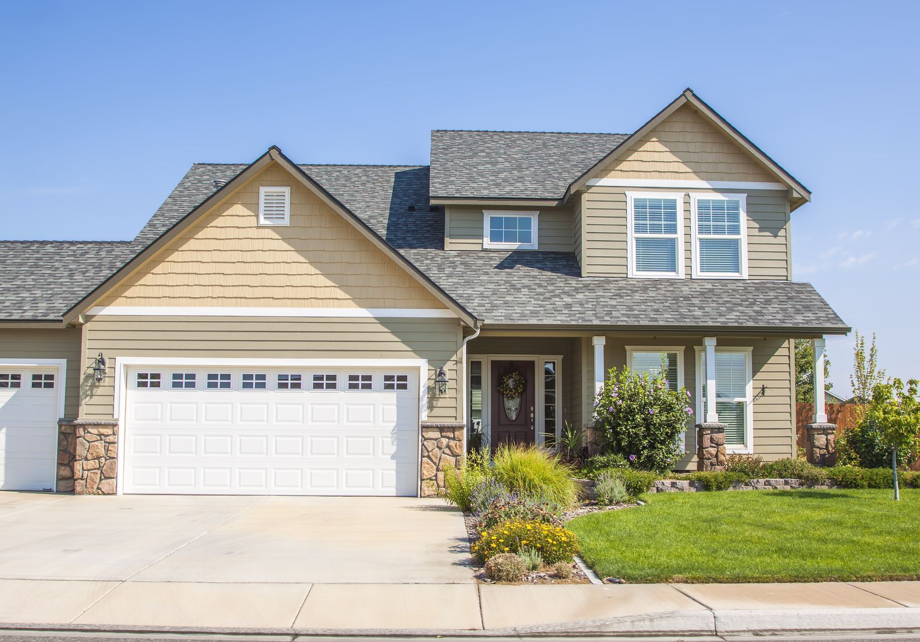 A large house with two garage doors and a gray roof