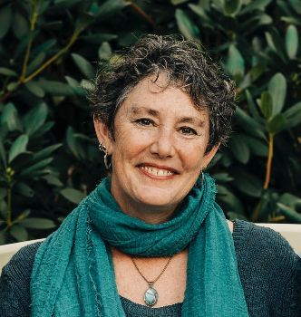 A woman wearing a green scarf and a necklace is smiling for the camera.