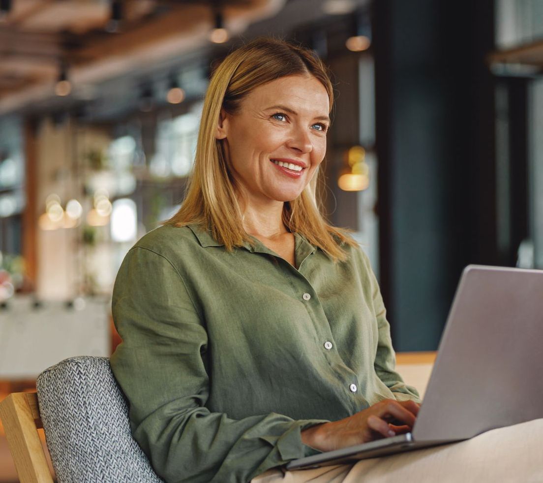 A woman is sitting in a chair using a laptop computer.