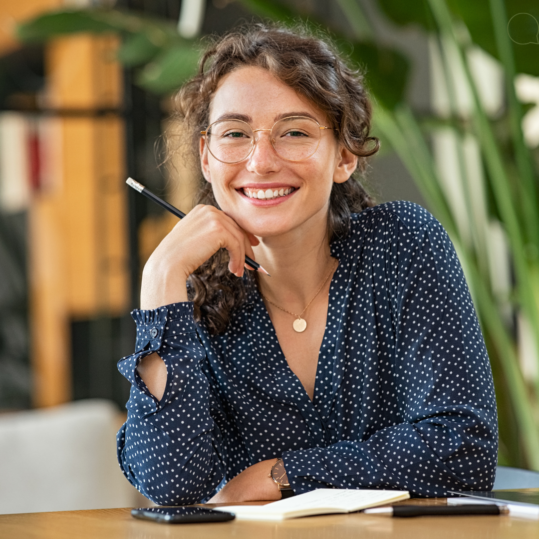 A woman is holding a tablet and smiling in an office.