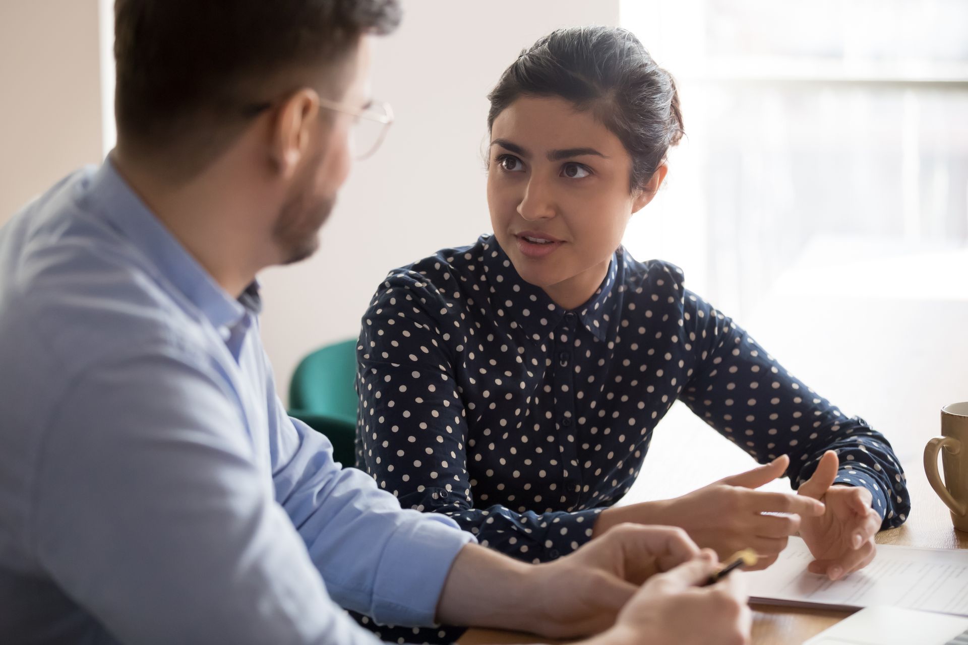 A man and a woman are sitting at a table having a conversation.