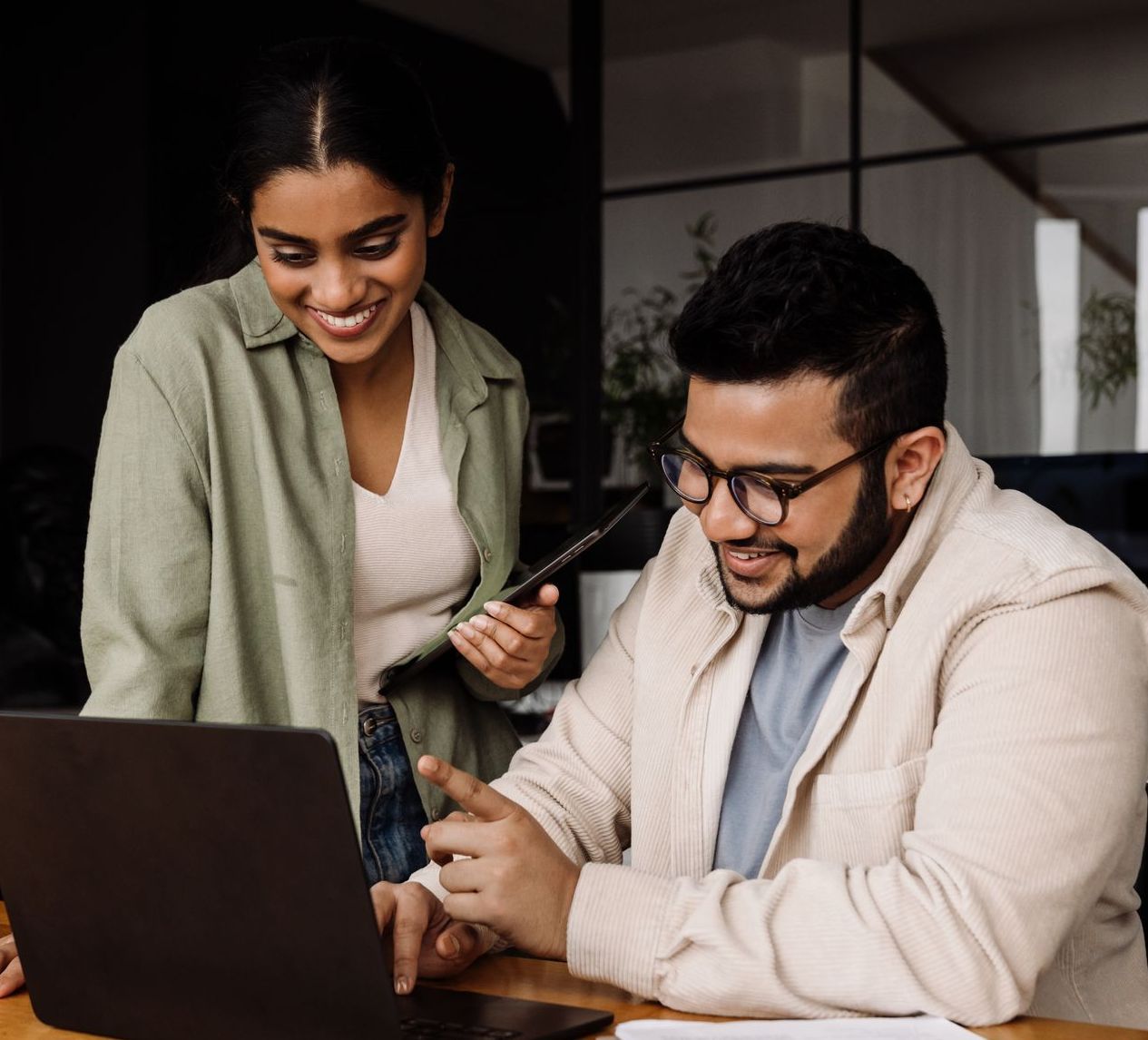 A man and a woman are looking at a laptop computer.