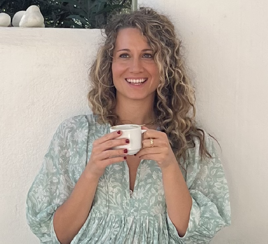 A woman is holding a cup of coffee and smiling