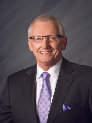 A man in a suit and tie is smiling for the camera.