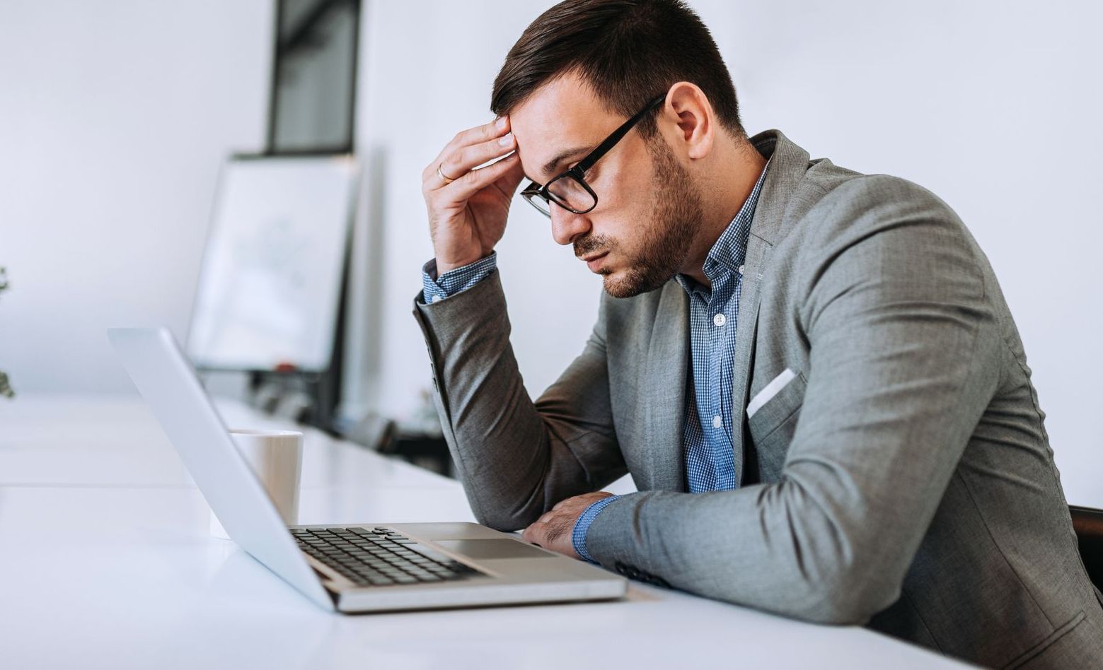 A man is sitting at a desk in front of a laptop computer.