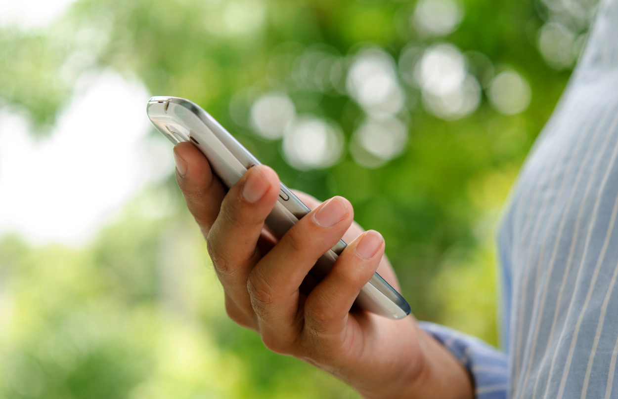 Woman with red hair and a yellow shirt smiles leaning against a white wall.
