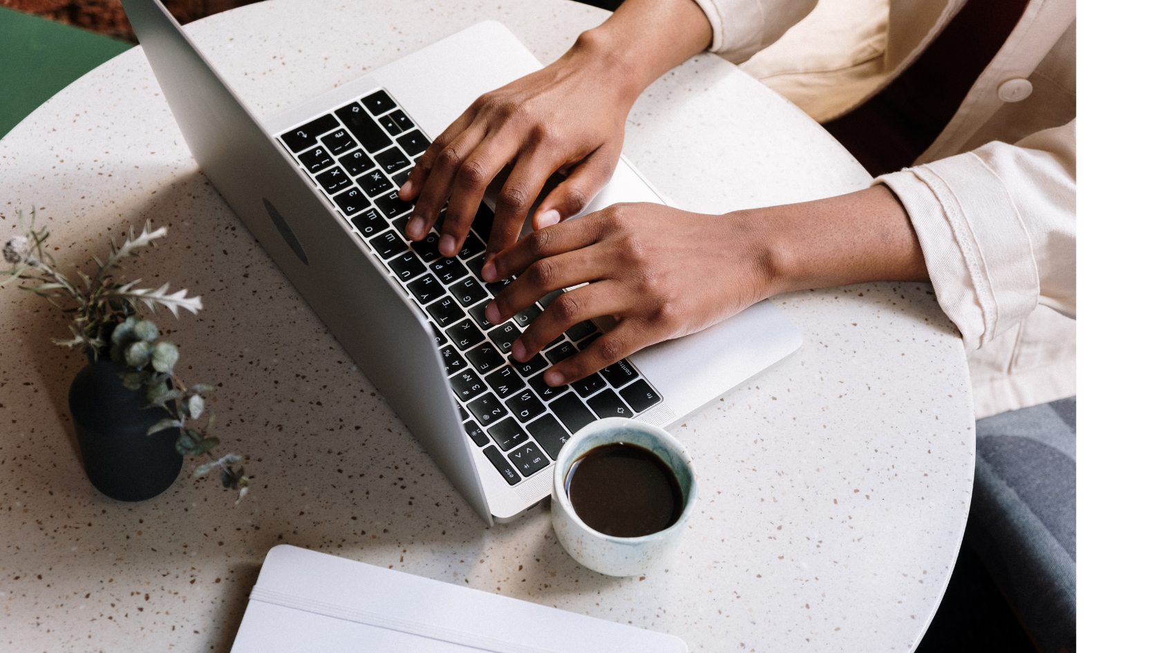 Woman in denim shirt smiles, holding a phone, sitting on a brown couch. Indoors, natural light.