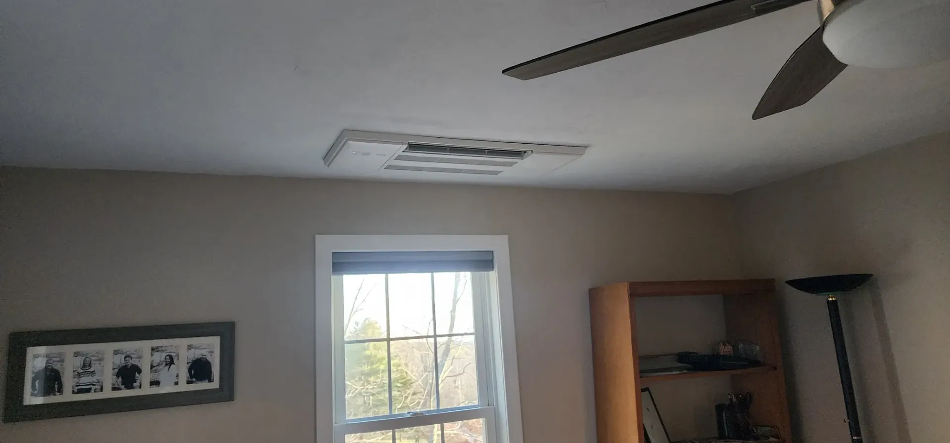 A bedroom with a ceiling fan and a window.