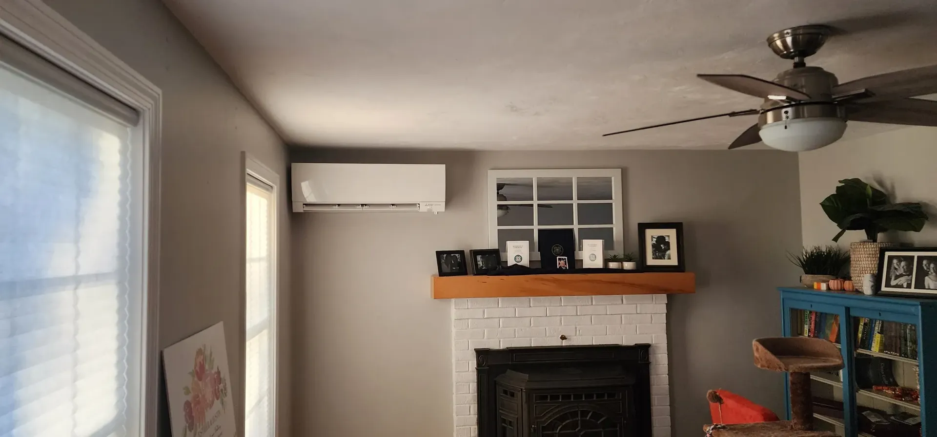 A living room with a fireplace and a ceiling fan.