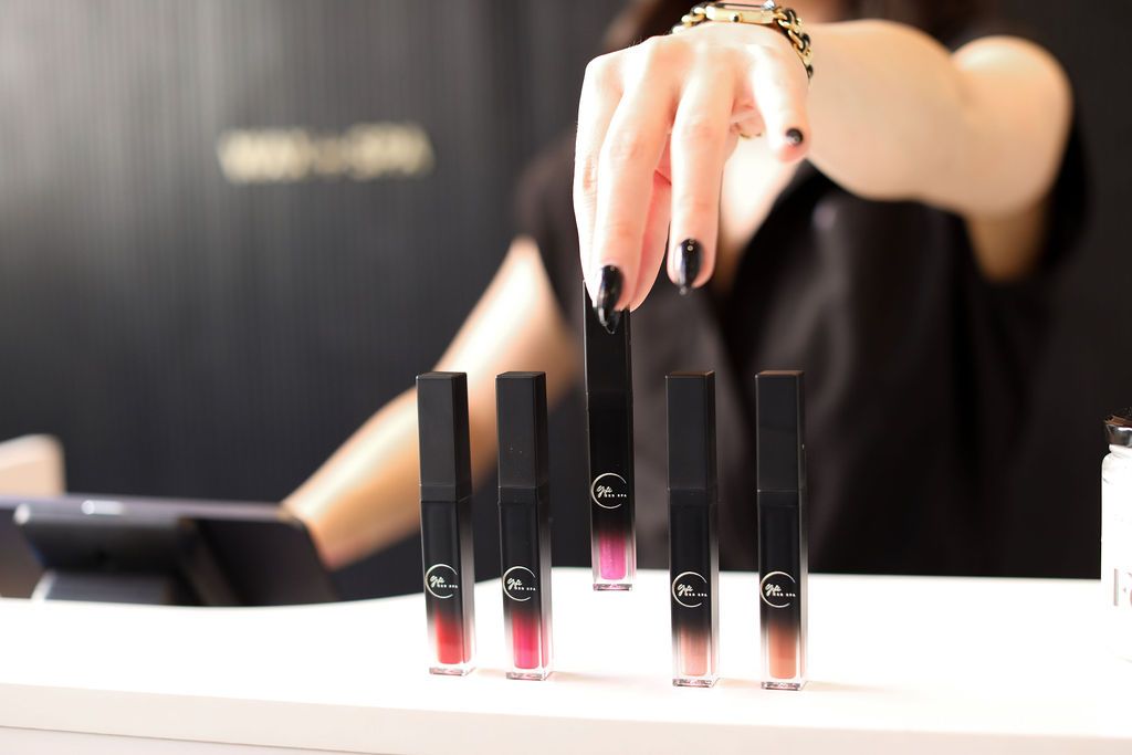 A woman is holding a row of lipsticks on a table