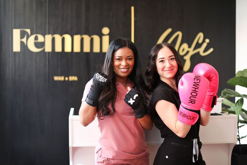 Two women wearing pink boxing gloves are posing for a picture.