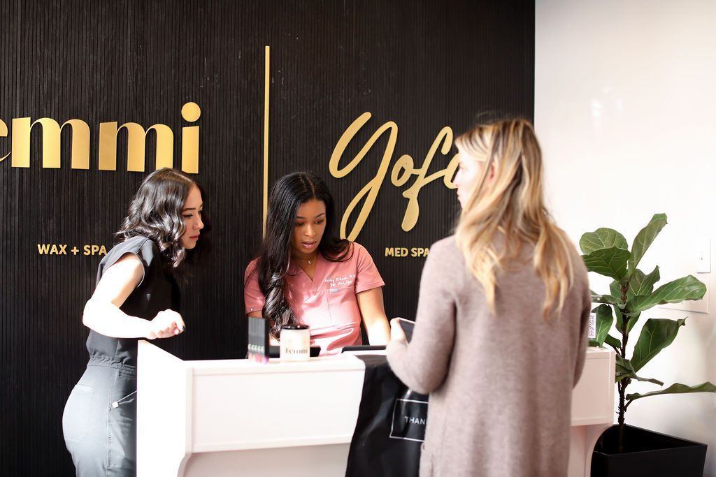 Two women are standing at a reception desk in a salon.